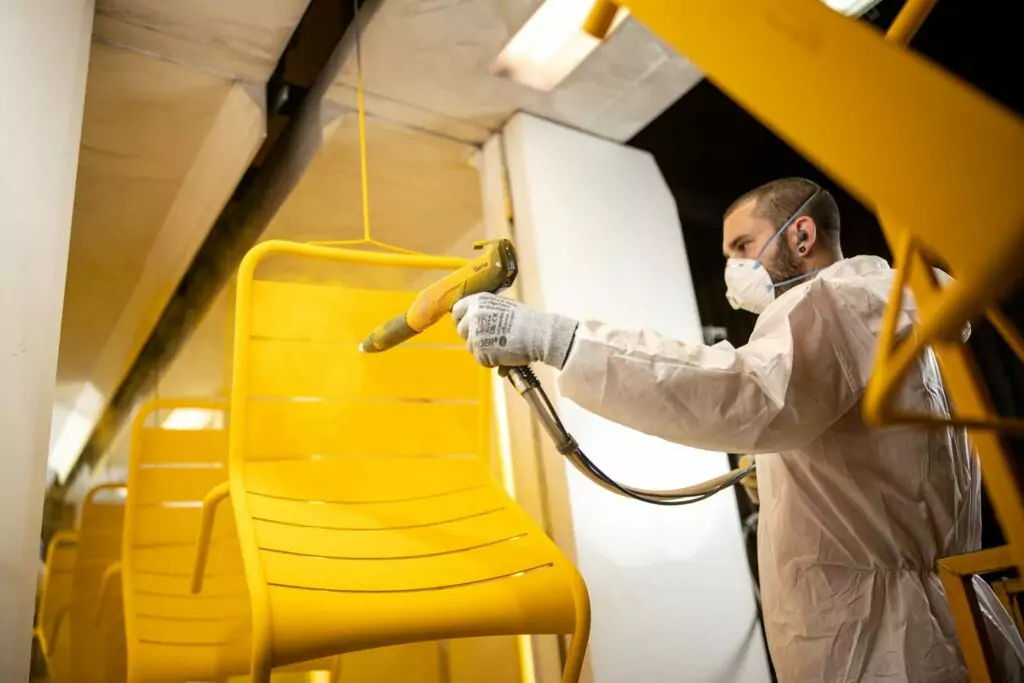 thermolaqueur en phase de poudrage d'une chaise jaune