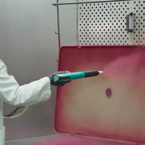 Professionnel du thermolaquage en train d'appliquer de la peinture en poudre sur une table en métal